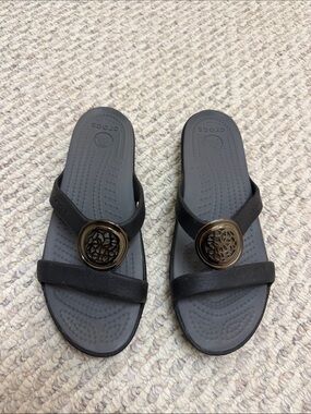 CROCS Women’s Black Slide Sandals with Bronze Decorative Medallion
